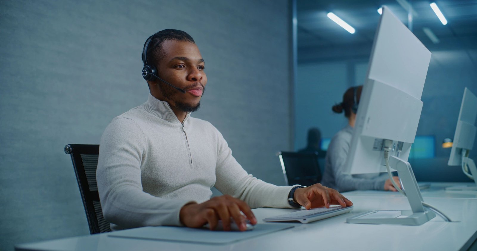 Customer support professional using a headset at a computer